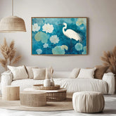 May include: A framed artwork featuring a white egret standing amidst white flowers and green lily pads against a teal background. The artwork is displayed above a white sofa with beige pillows. A woven pendant light hangs above a round, woven coffee table. The room has a neutral color palette.